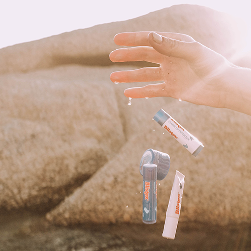 In sommerlicher Kulisse werden mehrere Blistex-Pflegeprodukte fallen gelassen.